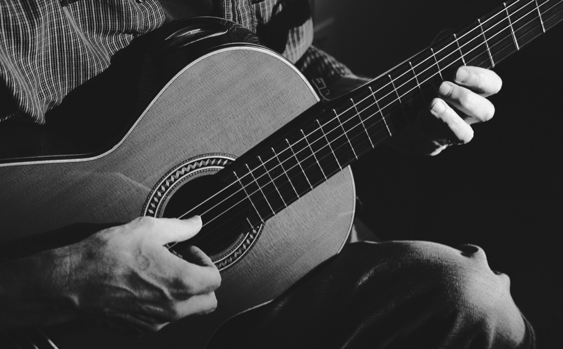 Close up image of a guitarist playing a nylon string guitar.